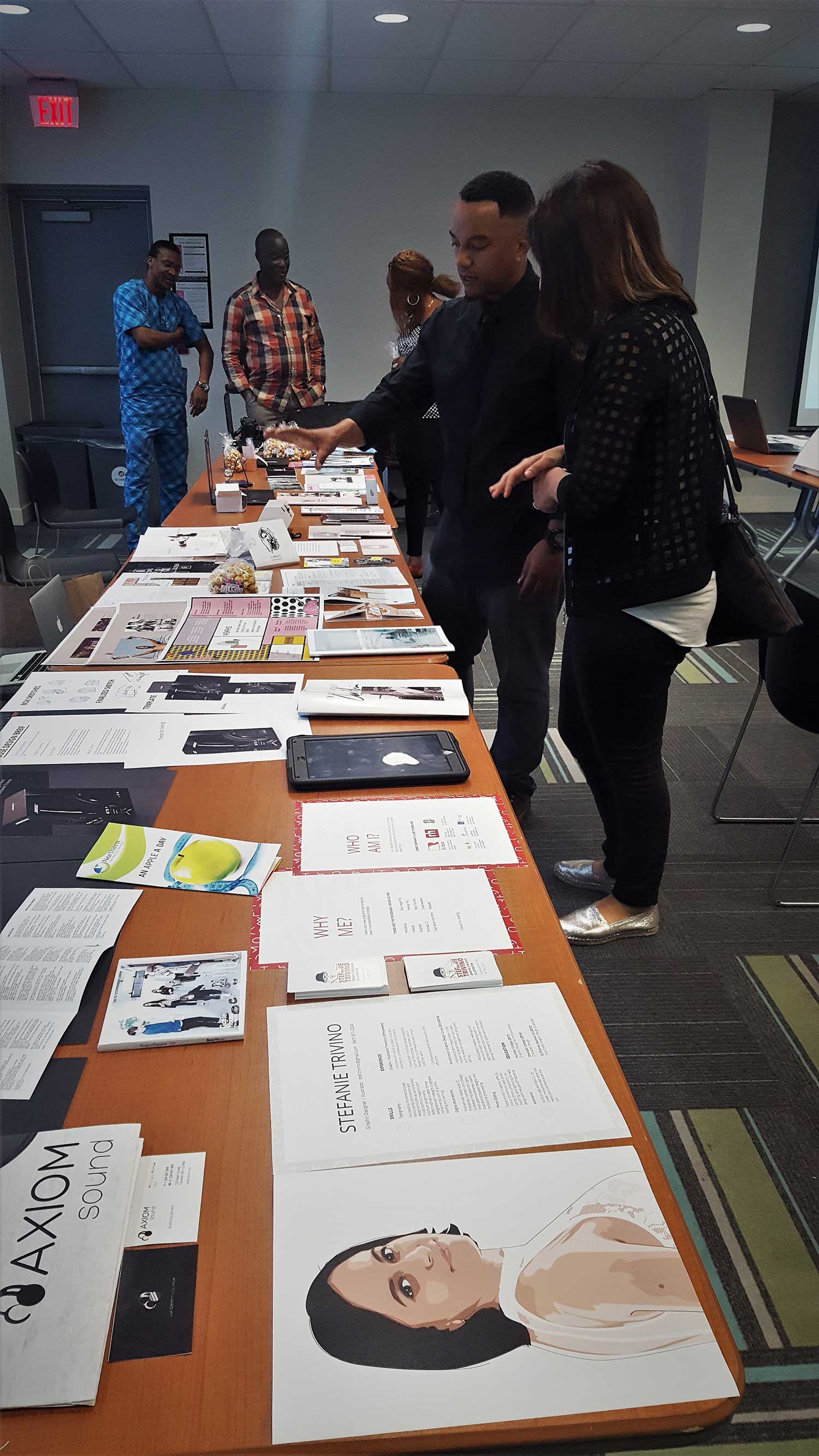 people looking at a long table of student work
