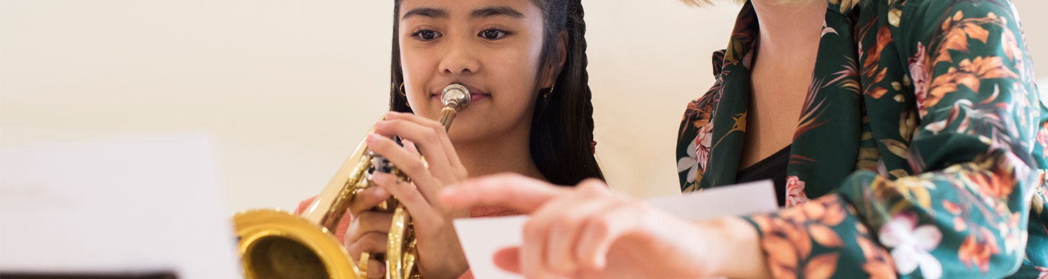 woman teaching young girl how to play the trumpet