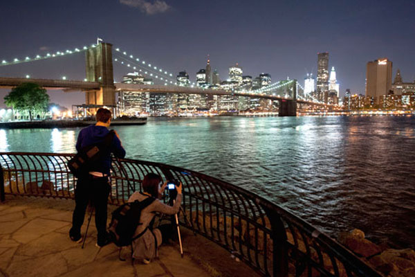 students taking night photos of a bridge over the water