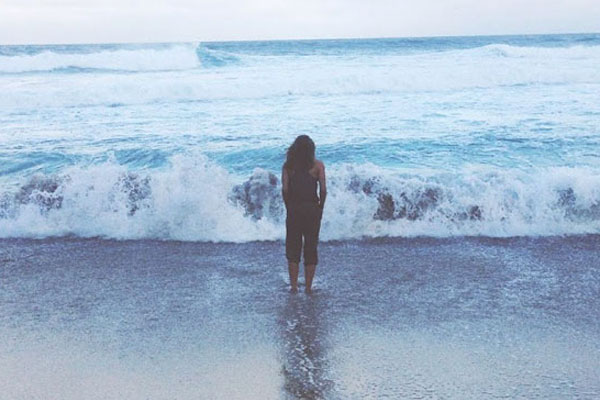 student standing on the beach looking at the ocean