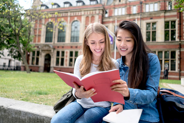 Two students reading book outside