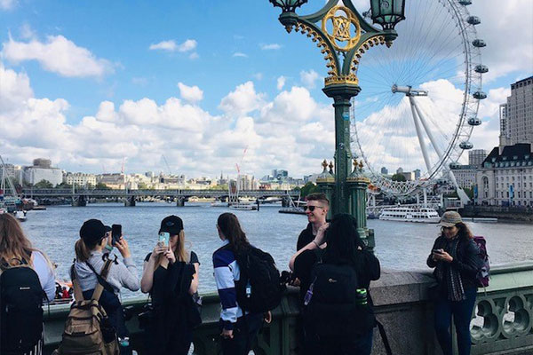Students taking a photo with the London Eye in the background