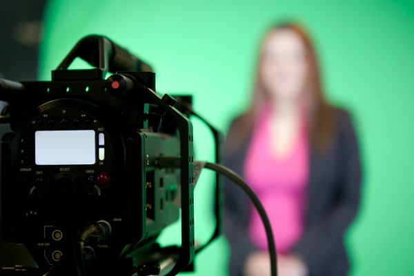 blurred student in the background on a green screen and back of camera in focus
