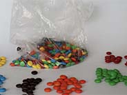 M&Ms in a bag and sorted by colour on a surface