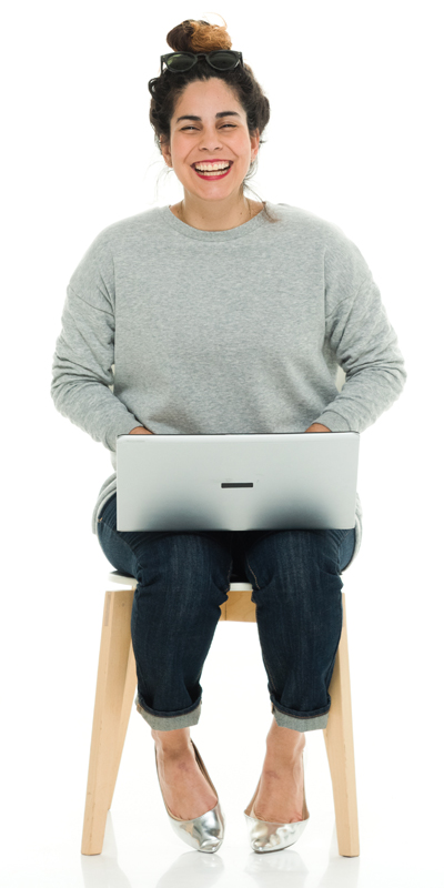 girl sitting on stool laughing with laptop on her lap