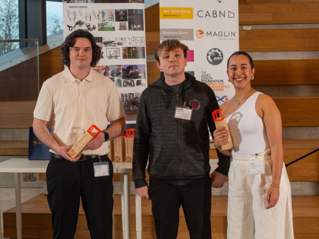 Two students holding awards pose with someone for photo