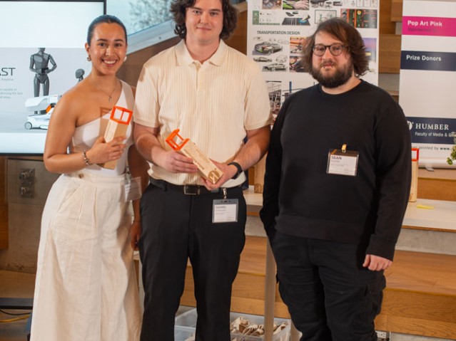 Two awarded students pose with person for photo