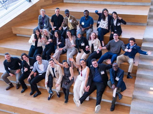 Group shot of Industrial Design graduating class and professors sitting on stairs making excited poses