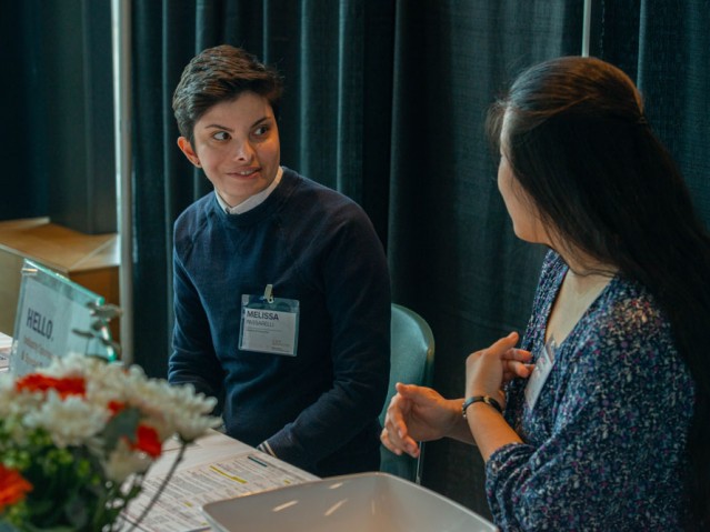 Two people sitting behind a table talking