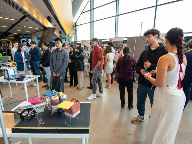 Student talks to event guest in front of their project display