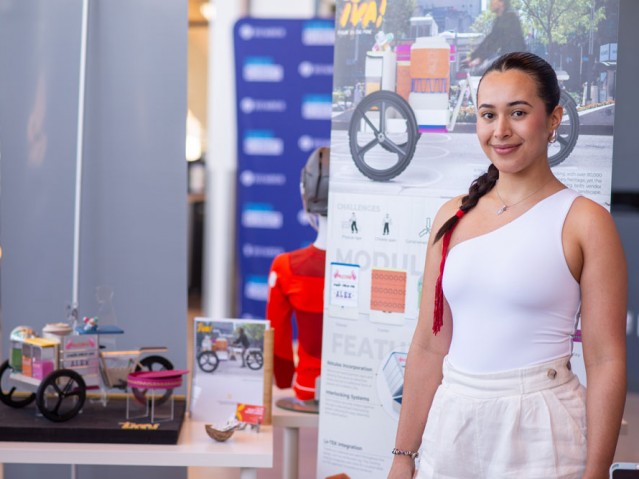 Student poses in front of their project poster