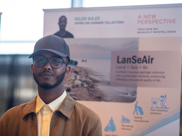 Student stands in front of his project poster