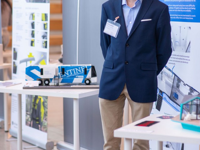 Student stands with his project display