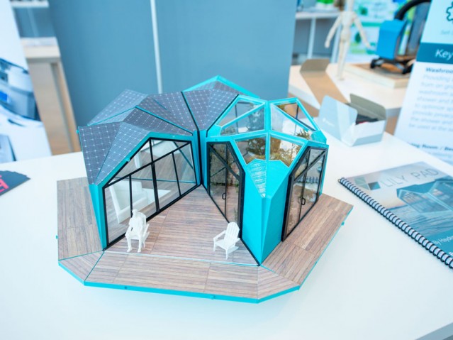 3D physical model of figure sitting in front of a small house design