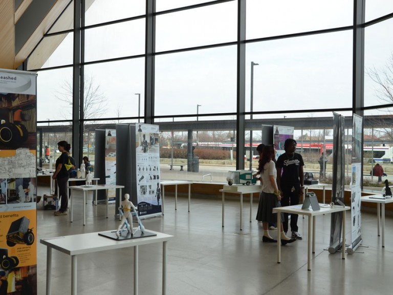 Atrium with a few people lingering around project posters