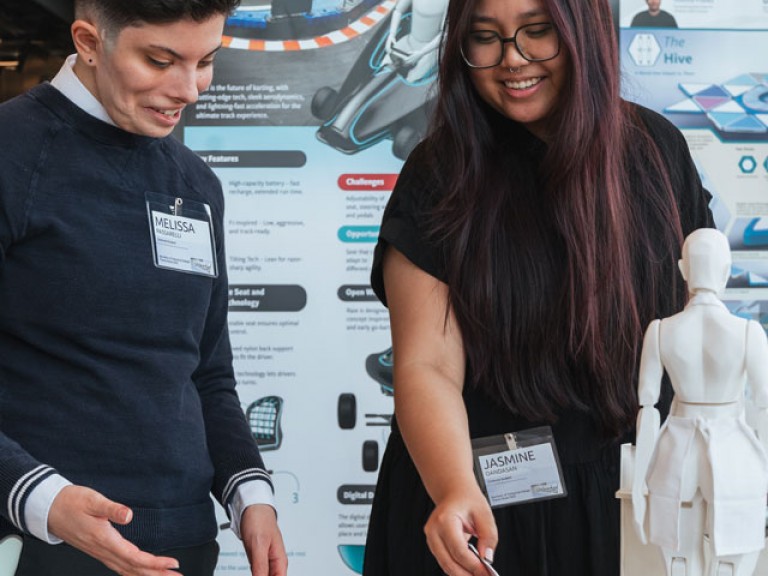 Two design graduates looking through book on table