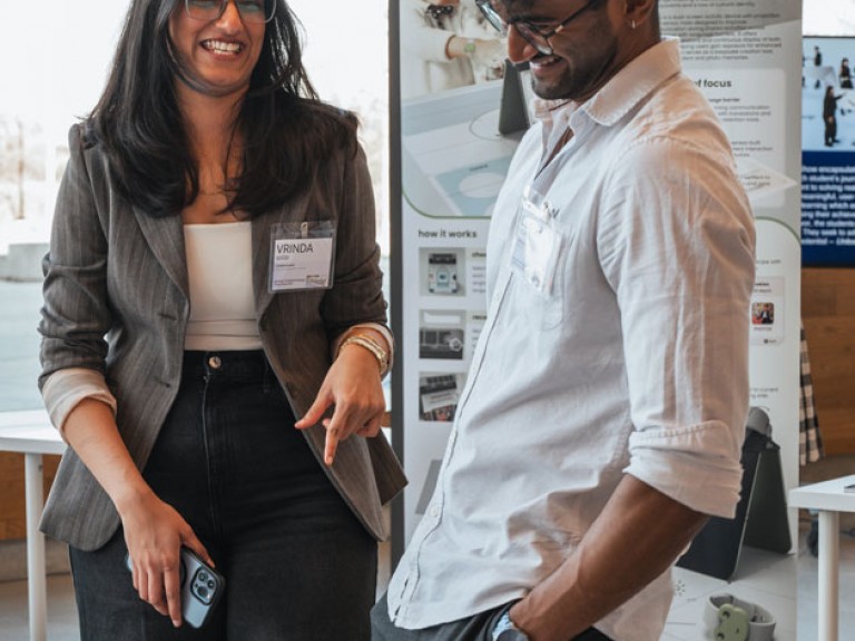 Two people laughing in front of project poster
