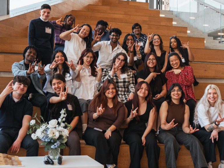 People holding up hands as they sit on steps for picture