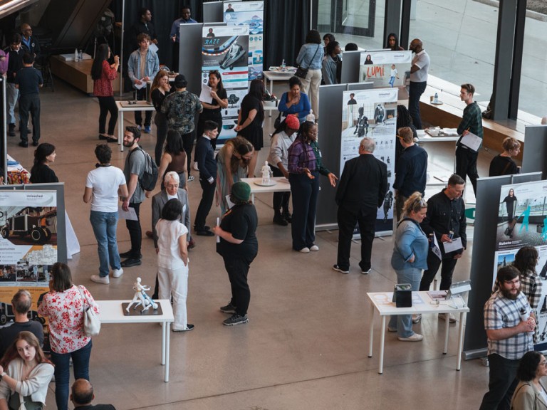 People mingling in atrium looking at student project displays