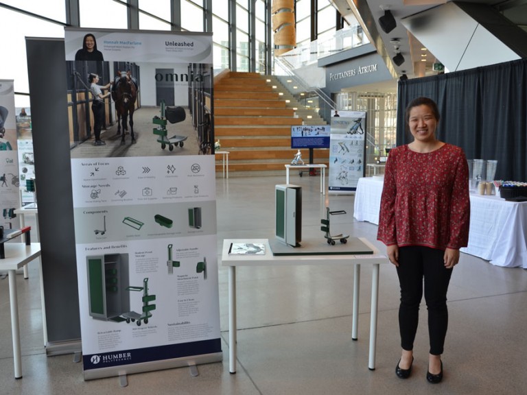 Industrial design graduate Hannah Macfarlane standing beside project display