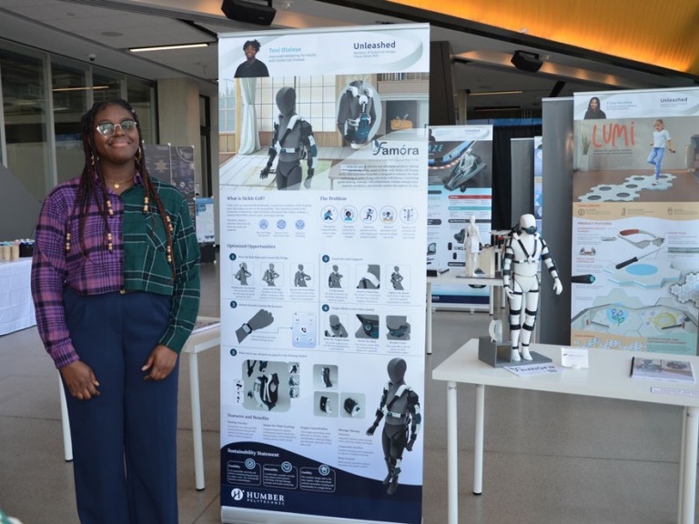 Industrial design graduate Toni Olaleye standing beside project display