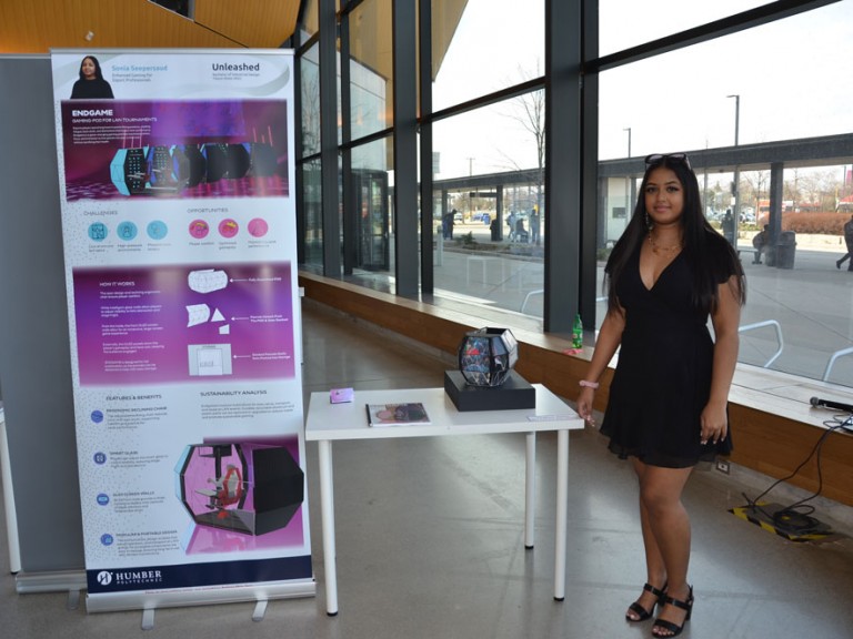 Industrial design graduate Sonia Seepersaud standing beside project display