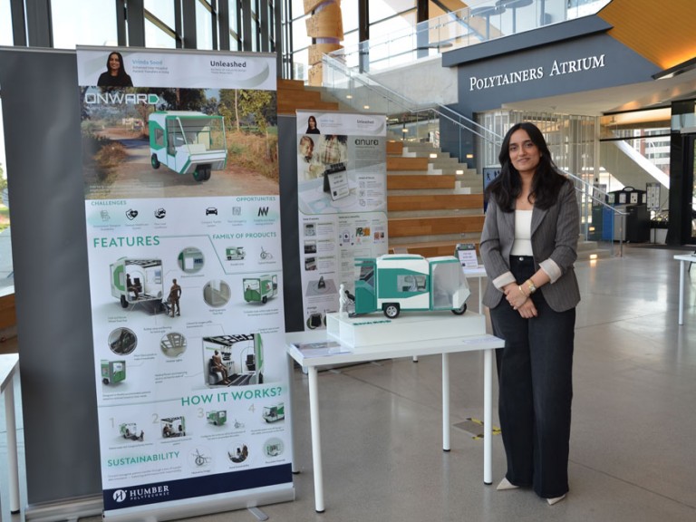 Industrial design graduate Vrinda Sood standing beside project display