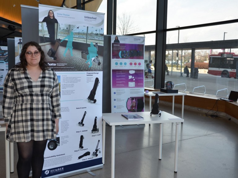 Industrial design graduate Emma Thomas standing beside project display