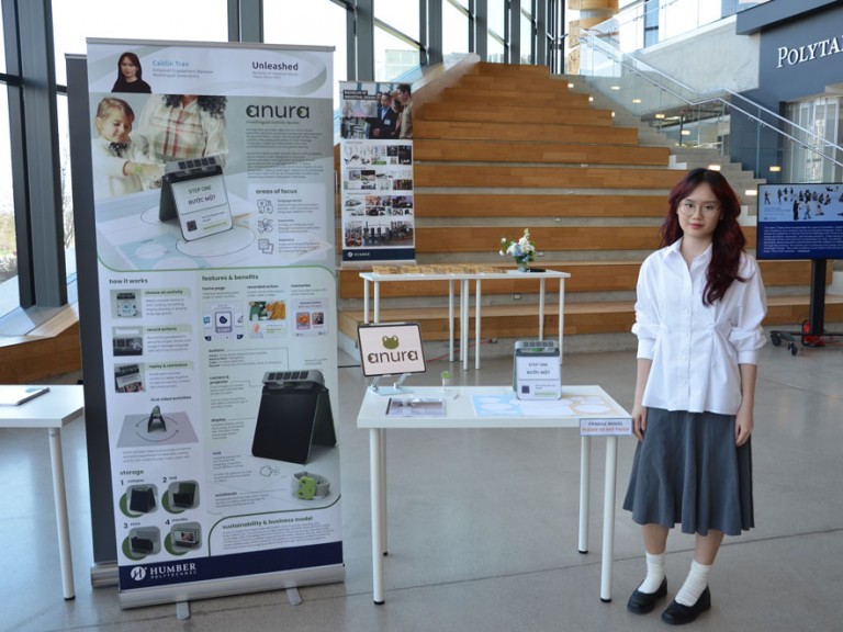 Industrial design graduate Caitlin Tran standing beside project display