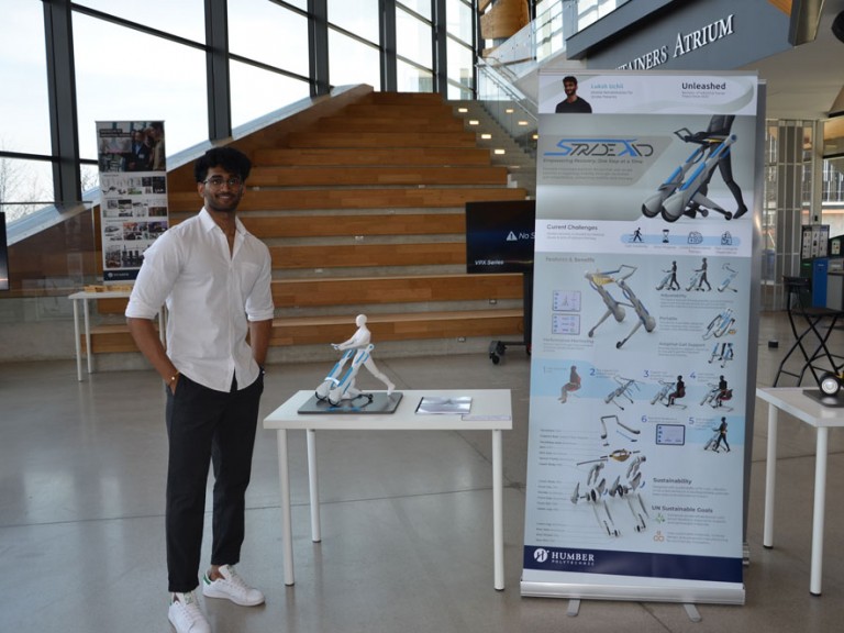 Industrial design graduate Luksh Uchil standing beside project display