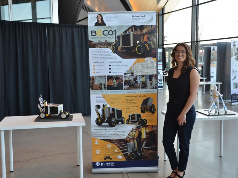 Industrial design graduate Aline Zarpelao standing beside project display