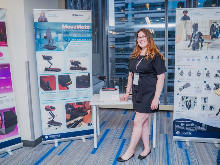 Industrial design graduate Ellie Camp standing beside project display