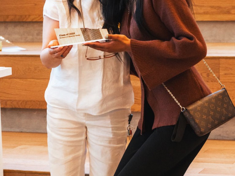 Design graduate and professor smiling for photo with award