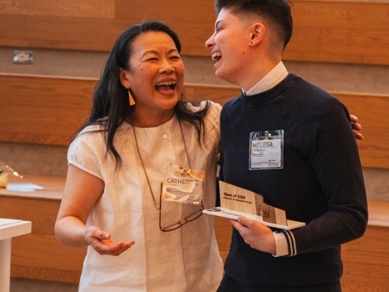 Design graduate and professor laughing with award