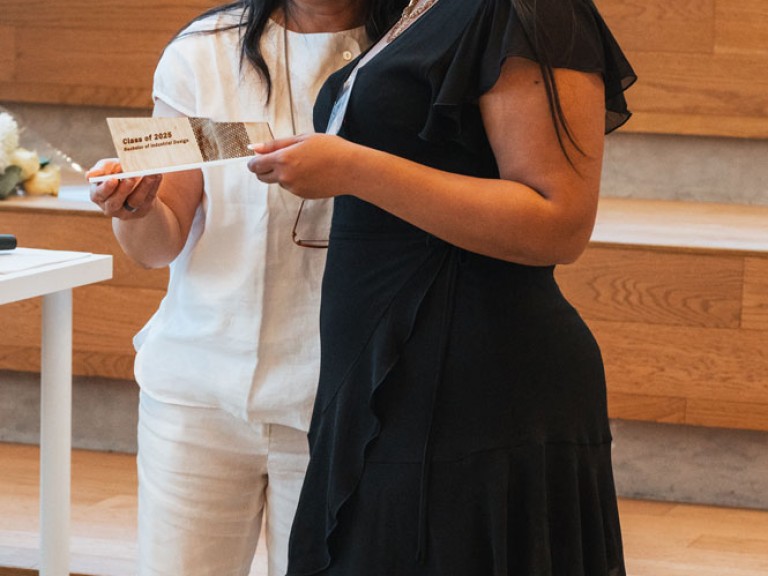 Design graduate and professor smiling for photo with award