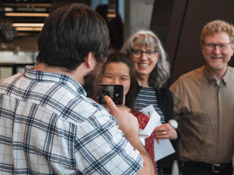 Person taking photo of others with their cell phone
