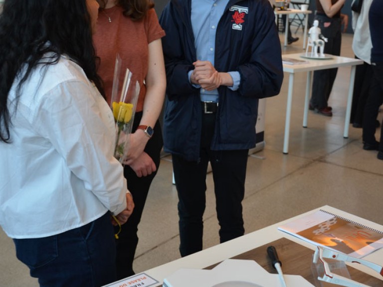Graduate talking to two event guests in front of their table