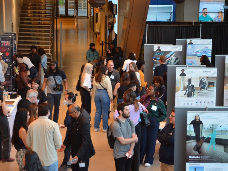 Overhead shot of people lingering around project displays in atrium