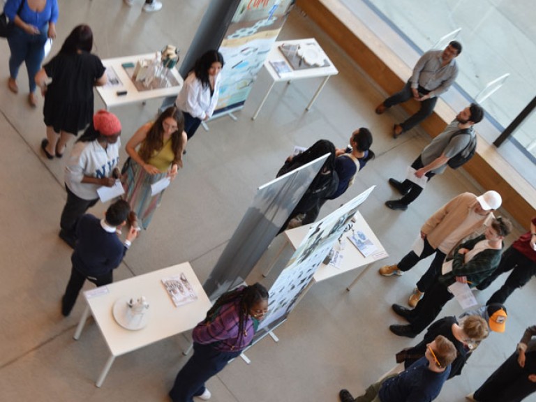 Overhead shot of people lingering around project displays in atrium