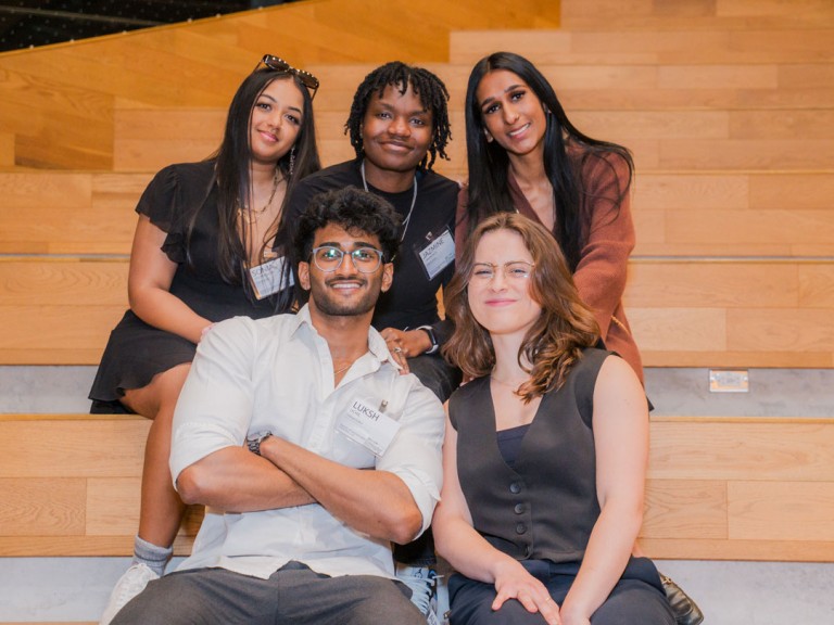 Five people sitting on steps posing for photo