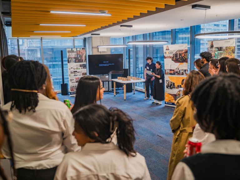 People standing around room watching two people in middle present