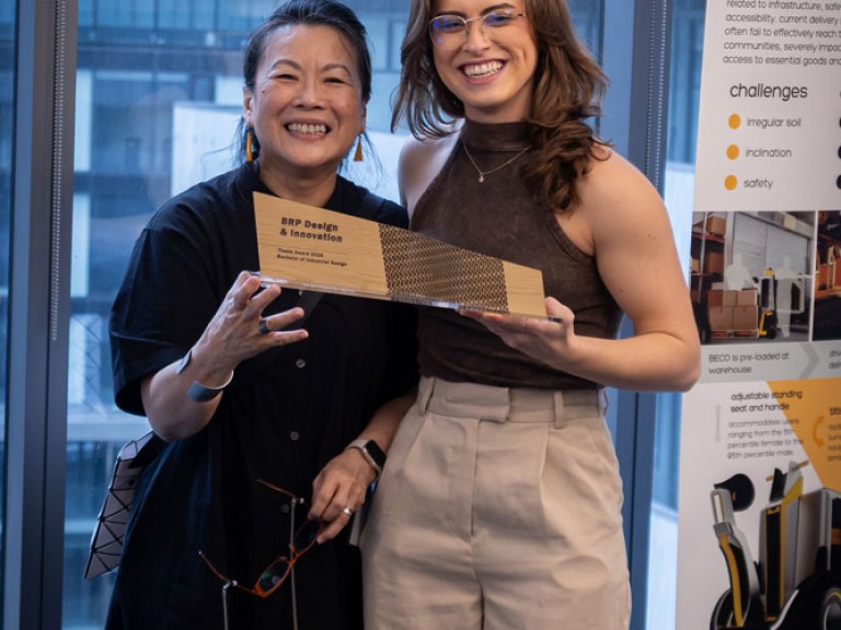 Industrial design graduate award winner and professor holding award and posing for camera