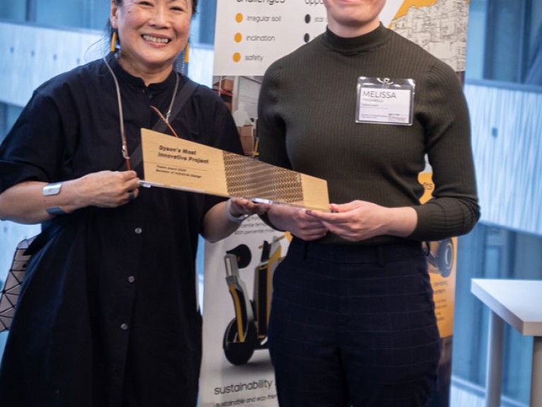 Industrial design graduate award winner and professor holding award and posing for camera