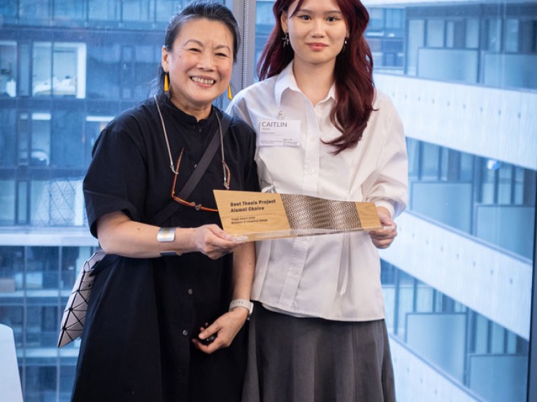 Industrial design graduate award winner and professor holding award and posing for camera