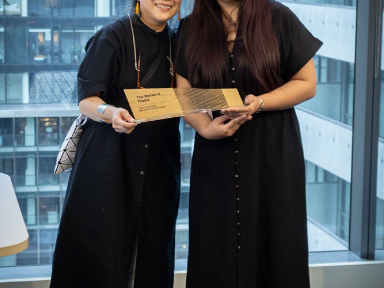 Industrial design graduate award winner and professor holding award and posing for camera