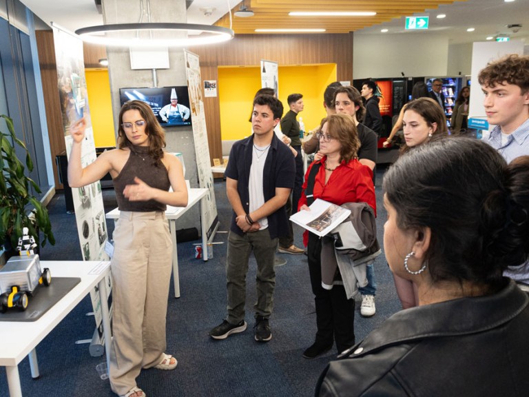 Event guests gathered around a graduate's project table